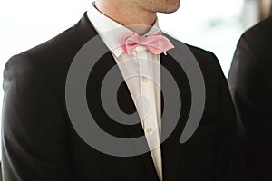 Elegant and stylish best men in black suits and pink bowties closeup