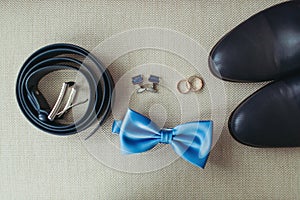 Elegant stylish dark male accessories on texture background. Top view of bloue bow-tie, shoes, wedding rings