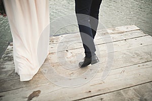 Elegant stylish groom with his happy gorgeous brunette bride on the background of a lake