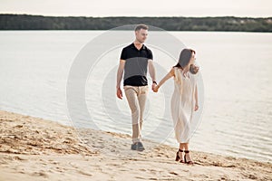 Elegant and stylish woman and man in love are walking along the lake. Happy moments together. love story