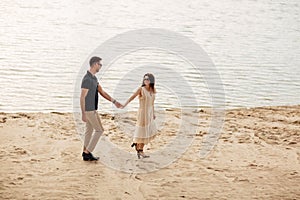 Elegant and stylish woman and man in love are walking along the lake. Happy moments together. love story