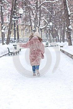 Elegant stylish woman in a pink fur coat, fluffy hat with earflaps, walking through the New Year\'s