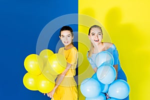 Elegant stylish women smiling and holding party balloons on blue