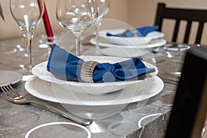 Elegant table set for a festive dinner in a restaurant. White plate, napkin and glassware