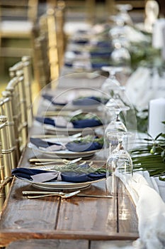 Elegant table set up for outdoor wedding reception with fine china and blue napkins