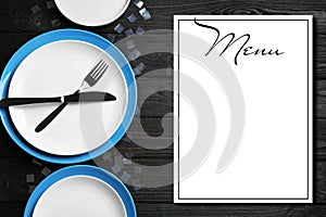Elegant table setting and empty menu on black background, flat lay. Space for text