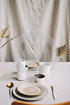 Elegant table setting for fine dining with cutlery, plates, cups on a linen tablecloth. Home decor rustic table setting