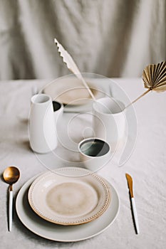 Elegant table setting for fine dining with cutlery, plates, cups on a linen tablecloth. Home decor rustic table setting