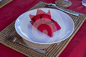 Elegant table setting with fork, spoon, white plate and red napkin in restaurant . Nice dining table set with arranged silverware
