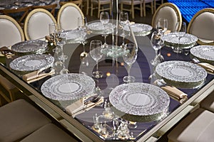Elegant table setting, luxury cristal plates for dinner, elegant ballroom for night wedding reception, flowers centerpiece