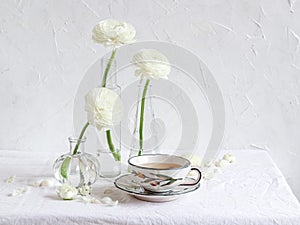 Elegant table setting with white ranunculus flowers and a cup of tea