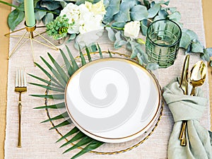 Elegant tableware for romantic dinner with greenery and flowers.