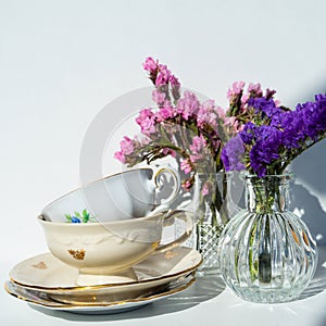 Elegant tea cups. White porcelain tea cups with a golden line decoration and a saucer on a white table. Vintage tea cups.