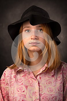 Elegant teen girl wearing black hat on dark background. Youth fashion.