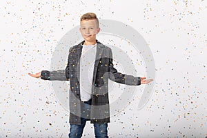 Elegant teenage kid wearing cool jacket standing in empty room, copy space on white wall