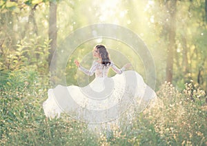 Elegant and tender girl with black hair in white elegant light dress, lady runs in forest, turning pretty face on camera