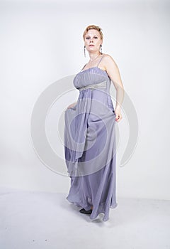 Elegant thick female in a grey long dress. pretty plus size woman in evening dress standing on white studio background. short hair