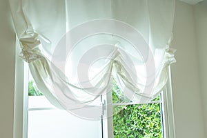 Elegant, thin transparent curtain folded by the window.