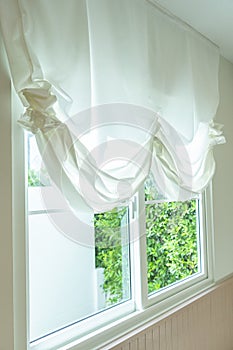 Elegant, thin transparent curtain folded by the window.