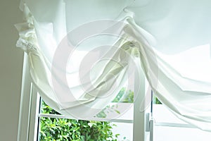 Elegant, thin transparent curtain folded by the window.