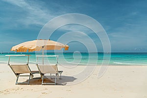 Elegant umbrella and sunbeds on white beach