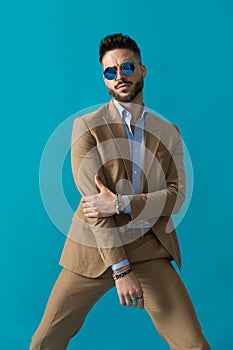Elegant unshaved young guy with retro glasses touching elbow
