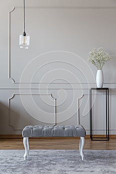 Elegant upholstered bench on a gray rug and flowers on a black t
