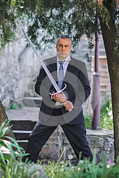 Elegant urban businessman warrior in suit with large medieval sword