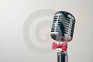 Elegant vintage microphone with red bowtie on white background exudes charm