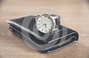 Elegant watch and wallet on wooden table