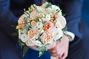 Elegant wedding bouquet in groom hand, beautifully decorated flowers closeup