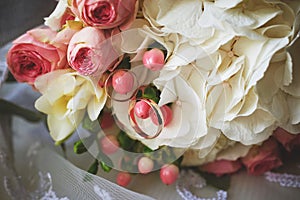 elegant wedding bouquet of white and pink rose flowers. gold wedding rings on the table. preparing for the wedding ceremony