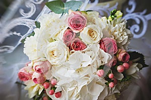 an elegant wedding bouquet of white and pink rose flowers. gold wedding rings on the table. preparing for the wedding ceremony