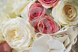 an elegant wedding bouquet of white and pink rose flowers. gold wedding rings on the table. preparing for the wedding ceremony