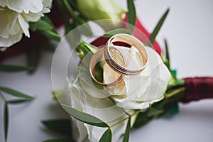 elegant wedding bouquet of white and pink rose flowers. gold wedding rings on the table. preparing for the wedding ceremony