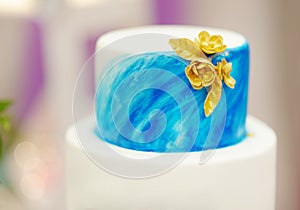 Elegant wedding cake with blue cake with golden flowers and cupcakes on wedding or event party