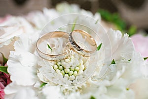 Elegant wedding engagement rings in white and yellow gold on a white flower