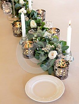 Elegant wedding floral decoration with white burning candles,roses and eucalyptus.
