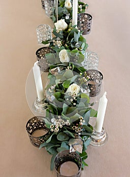 Elegant wedding floral decoration with white candles,roses and eucalyptus.