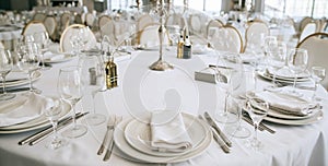 Elegant wedding reception white table arrangement restaurant, candlestick on table. Plates, forks and glasses