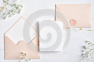 Elegant wedding stationery set. Wedding invitation card mockup, pastel pink wedding envelopes, flowers on stone table. Flat lay,