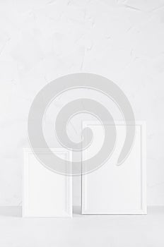 Elegant white empty rectangle photo frames standing on white wood table in simplicity delicate modern minimal soft light interior.