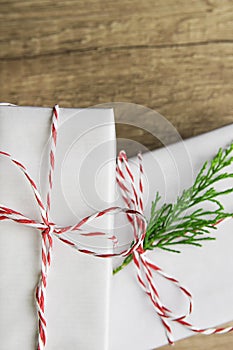 Elegant White Gift Boxes Tied with Red Ribbon Green Juniper Twig Stacked on Wood Tabletop Background. Christmas New Years Presents
