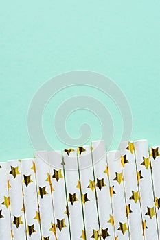 Elegant White Paper Drinking Straws with Golden Stars Pattern Scattered as Border on Turquoise Background. Birthday Party Fun Kids