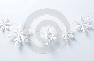 Elegant white snowflake garland featuring intricate paper designs, strung on a delicate thread. Perfect for winter decor photo