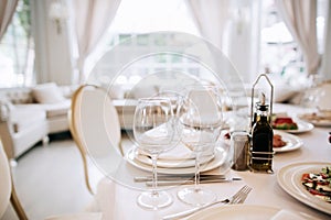 Elegant white table set. Served table in restaurant with dishes and glasses