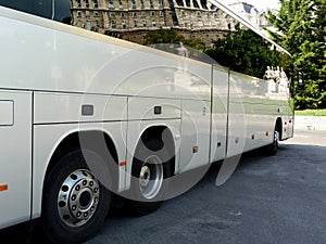 White tour bus with dark windows reflecting the castle building in Budapest