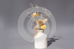 Elegant white vase with dried flowers in soft gray setting