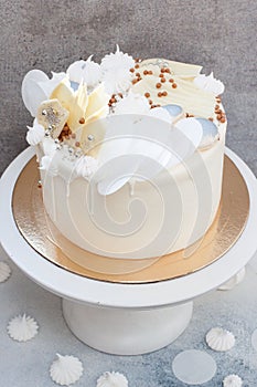 Elegant white wedding cake with chocolate decoration, meringues and macaroons