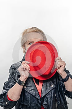 Elegant woman at the age, in a red hat and a red sweater.older model posing in studio. Youth in older age concept